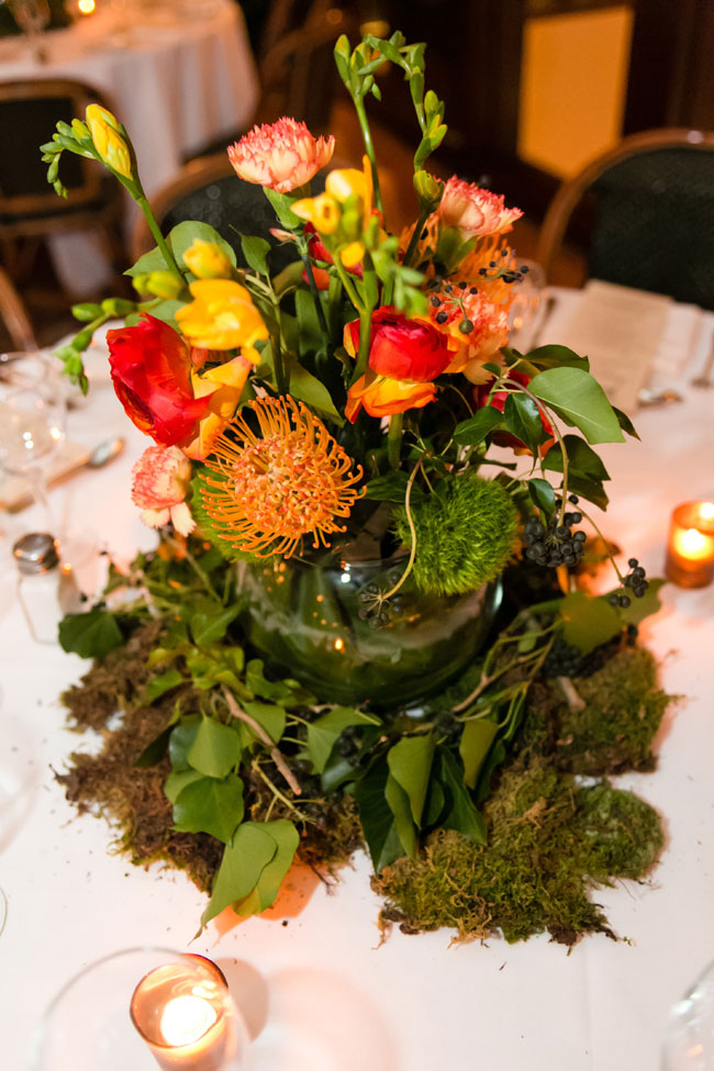 Winter Wedding Colors In Hues Of Reddish-Orange, Yellow & Green Create A Fireside Color Palette | Yellow Freesia, Pin Cushion Protea, Ranunculus, Carnation, Green Trick Dianthus Earthy Centerpiece