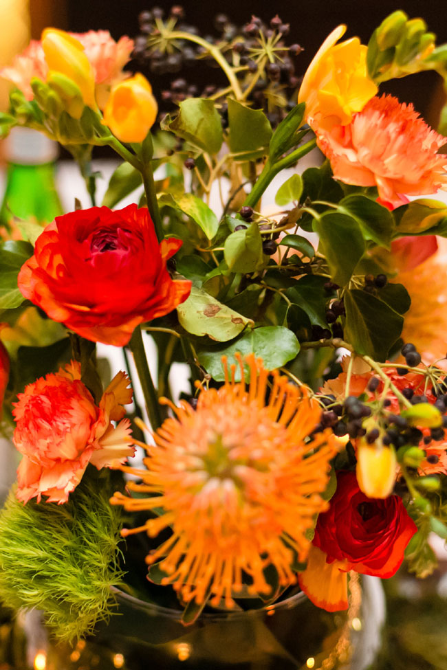 Winter Wedding Colors In Hues Of Reddish-Orange, Yellow & Green Create A Fireside Color Palette | Yellow Freesia, Pin Cushion Protea, Ranunculus, Carnation, Green Trick Dianthus Earthy Centerpiece